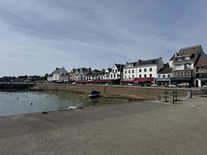 Eine Reihe heller Häuser schmiegt sich an eine geschützte Bucht mit ruhigem Wasser.